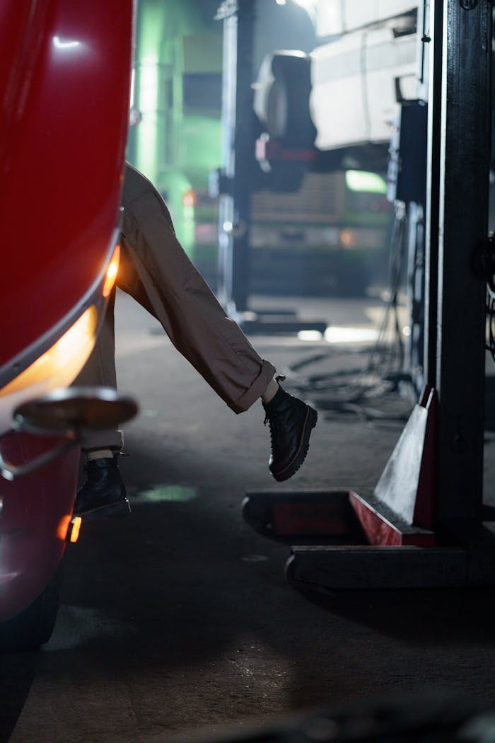 A mechanic working in a dimly lit garage, focusing on vehicle maintenance.